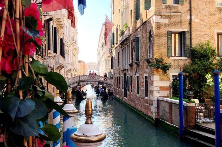Un canal estrecho en Venecia, Italia, con edificios a ambos lados, un puente en el centro y góndolas sobre el agua. 4