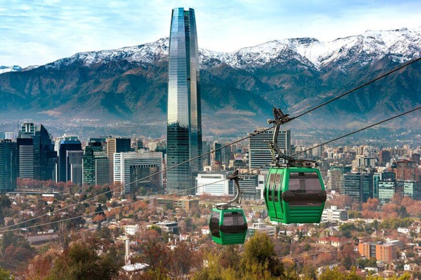 A cityscape with a prominent skyscraper, a cable car system, and snow-capped mountains in the background. 2