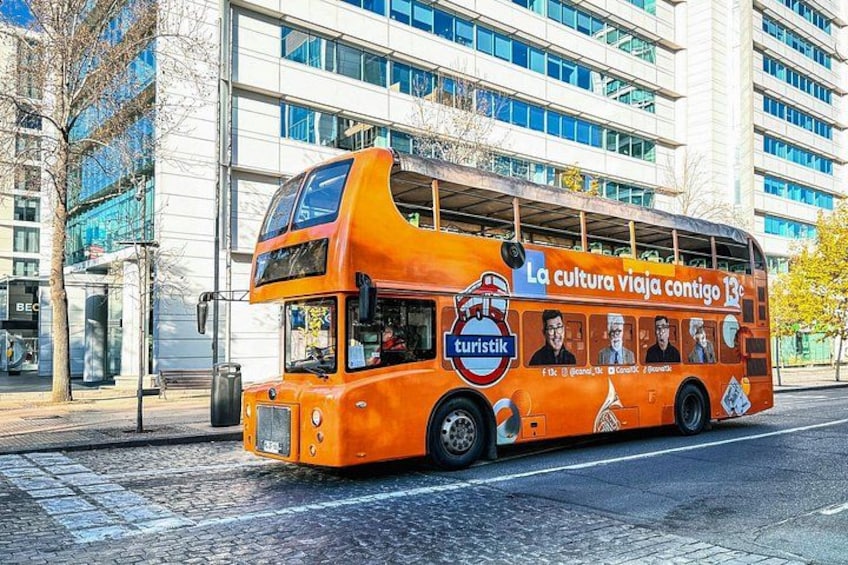 Un autobús de dos pisos con anuncios publicitarios en sus laterales, estacionado en una calle de la ciudad. 3
