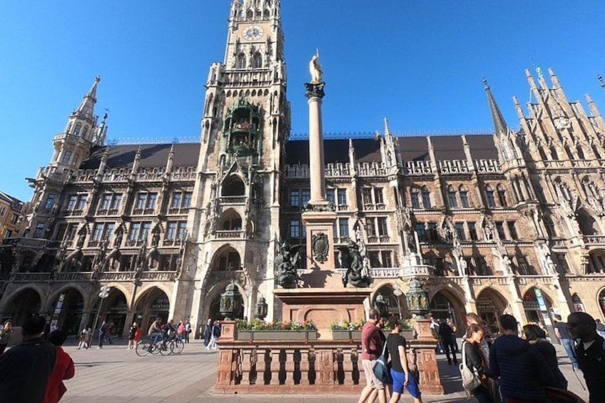 A historic building with intricate architecture, a prominent clock tower, and a statue in the center. 3