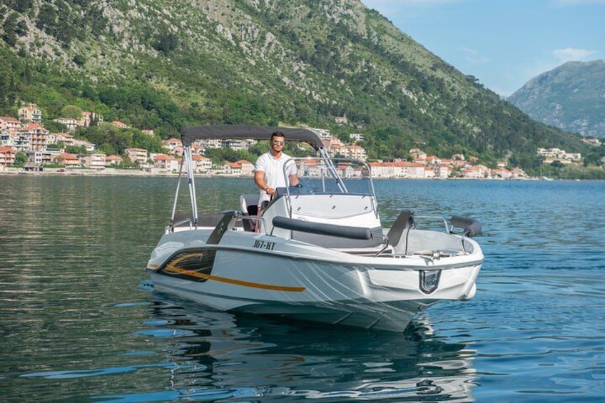 Una lancha blanca con una persona a bordo, flotando sobre aguas tranquilas con un paisaje montañoso al fondo. 2