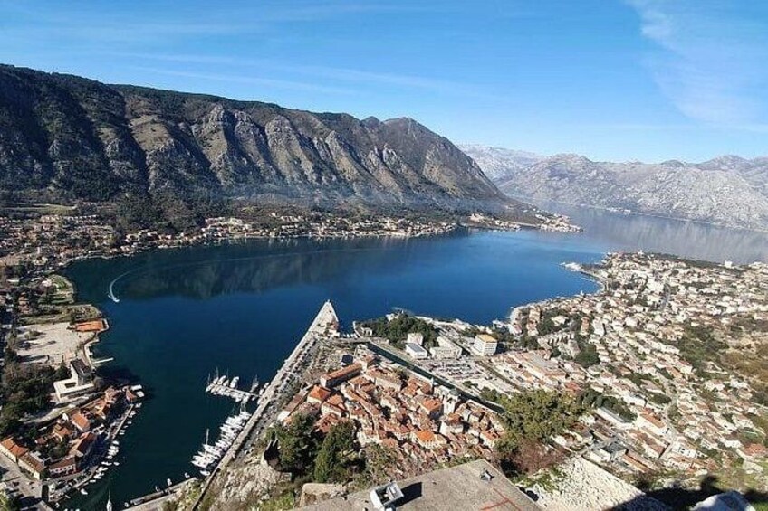 A coastal town with a marina, mountains in the background, and a clear sky. 2
