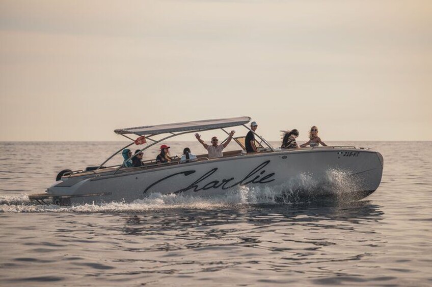 Een speedboot met de naam "Charlie" op de zijkant, die door rustig water vaart. 3
