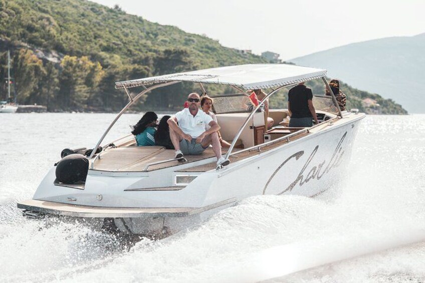 Een witte speedboot met de naam "Chalet" op de zijkant, vaart over een wateroppervlak met een bergachtig landschap op de achtergrond. 2