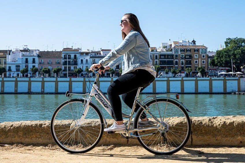 A person riding a bicycle along a waterfront with buildings in the background. 2