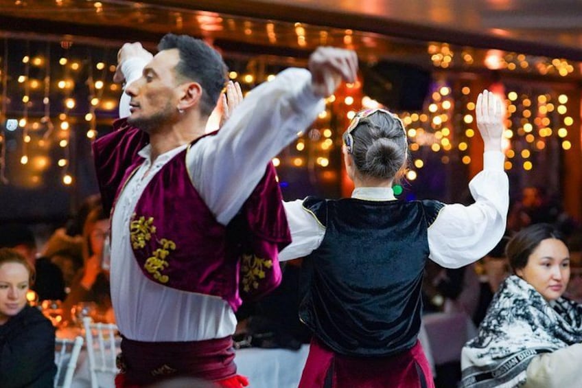 Une personne vêtue d’une chemise blanche et d’un gilet bordeaux, en train de danser. 3