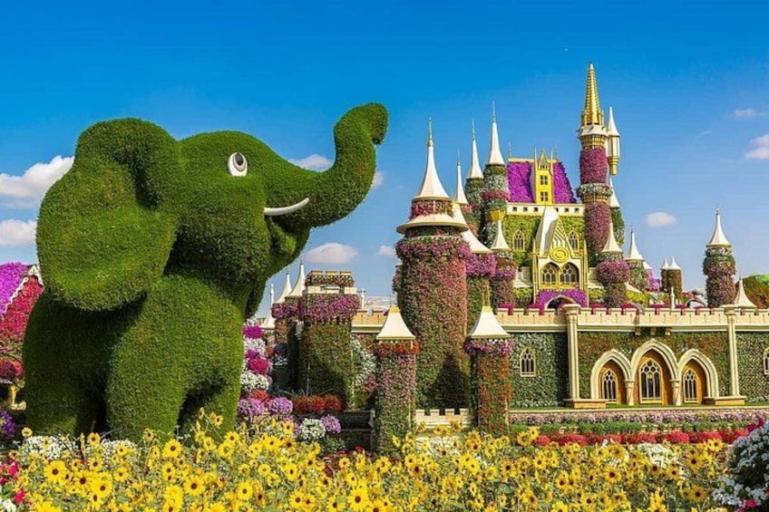 Una gran escultura de elefante verde, un castillo con torres y un campo de girasoles. 1
