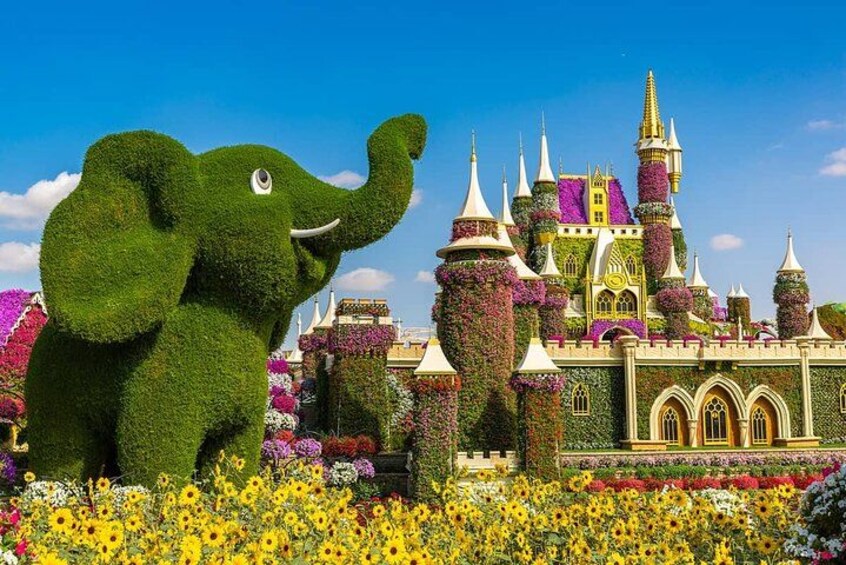 A large green elephant statue, a castle with multiple towers, and a field of sunflowers. 1