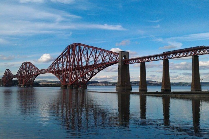 A red steel bridge over calm water with a clear sky. 5