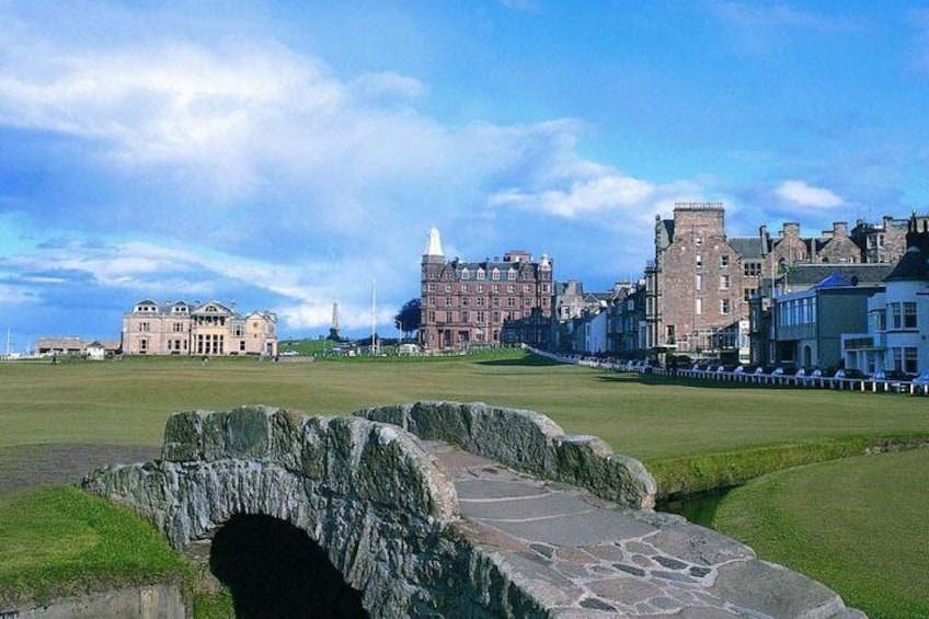 A stone bridge, historic buildings, and a lighthouse in a coastal town. 1