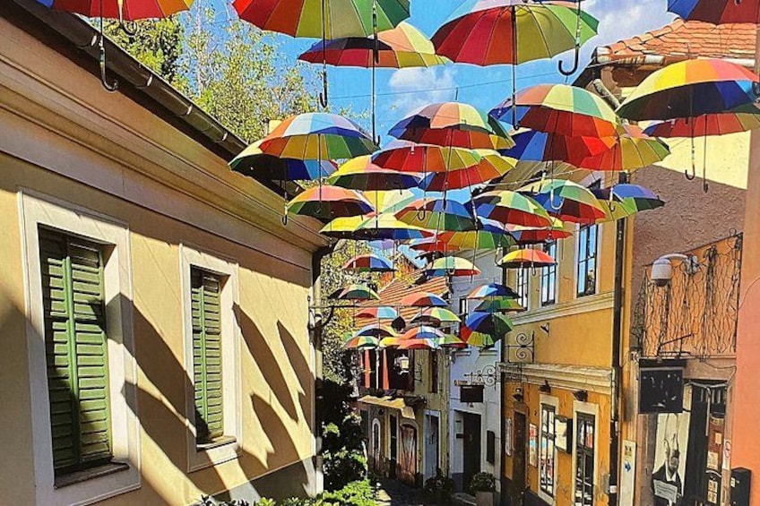 Una calle con paraguas de colores colgando sobre ella. 1