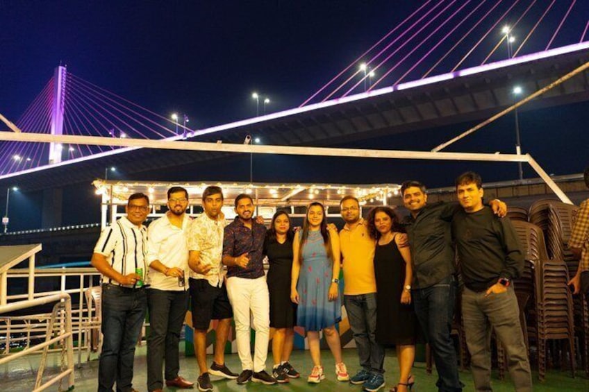 A group of people standing on a bridge at night with a city skyline in the background. 3