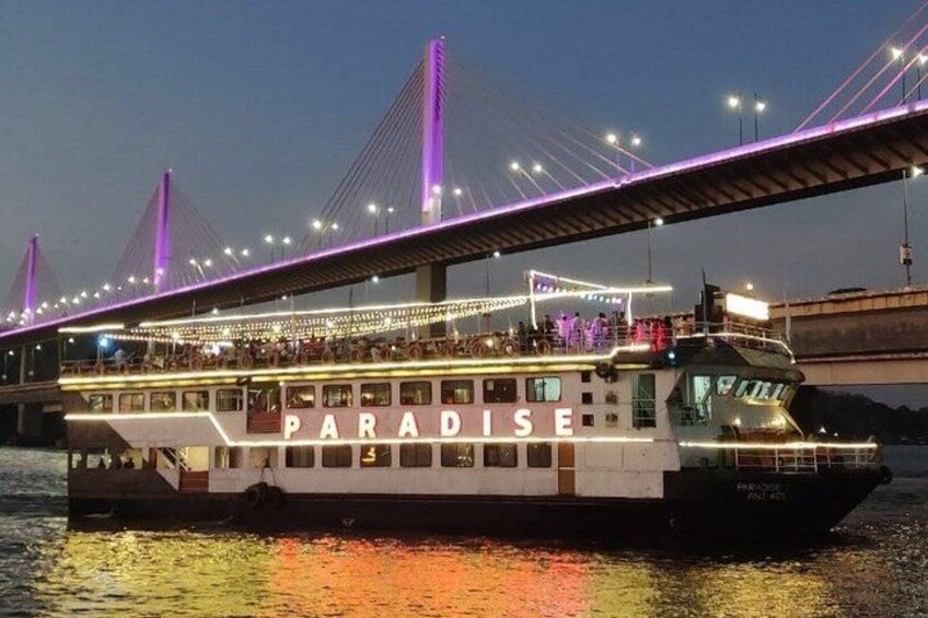Un barco de crucero fluvial llamado 'PARADISE' con un puente al fondo. 1