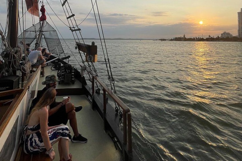 Un bateau avec des personnes sur le pont, un coucher de soleil et une côte en arrière-plan. 4