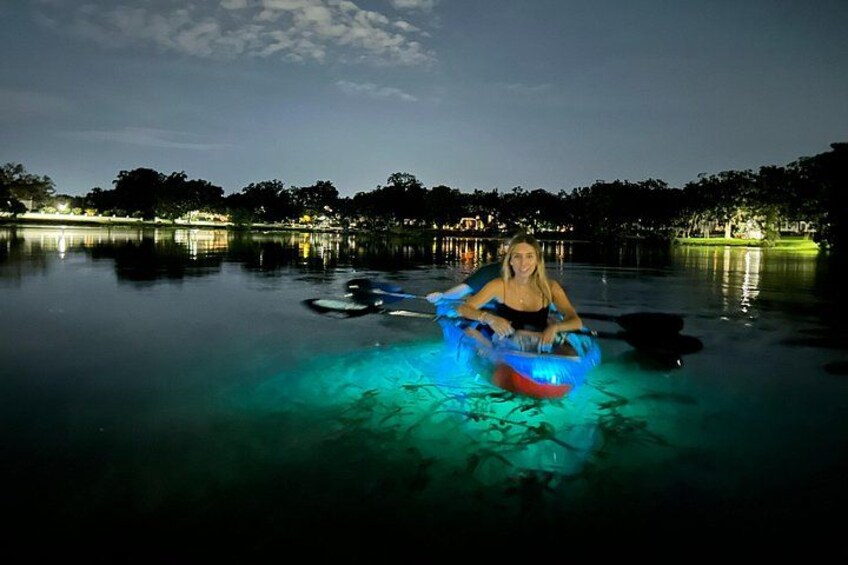 A person in a blue inflatable raft on a calm body of water at night. 1
