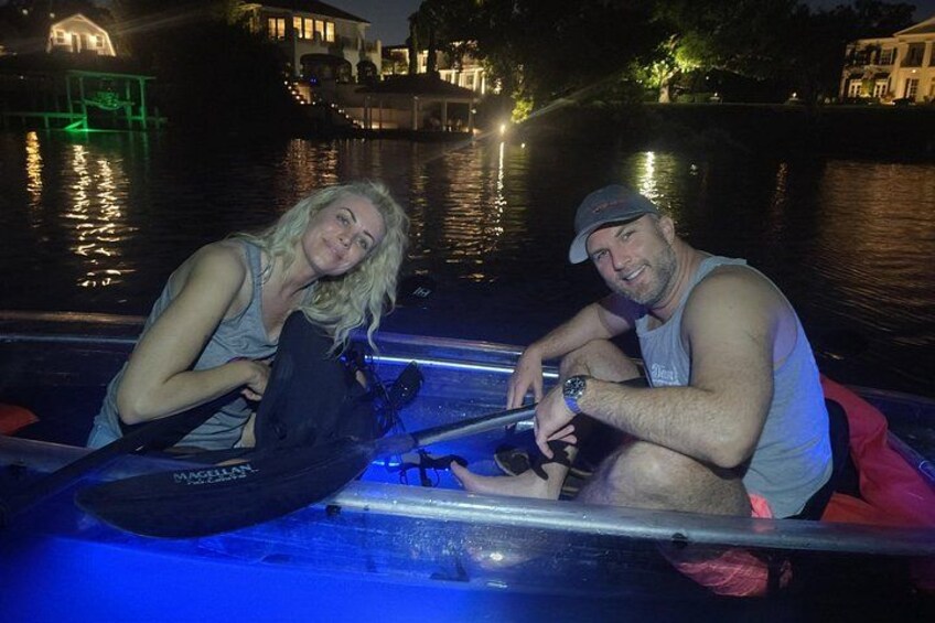 Two people in a boat on a body of water at night with buildings in the background. 2