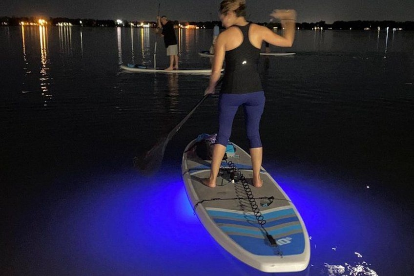 A person standing on a paddleboard in the water, holding a paddle. 3