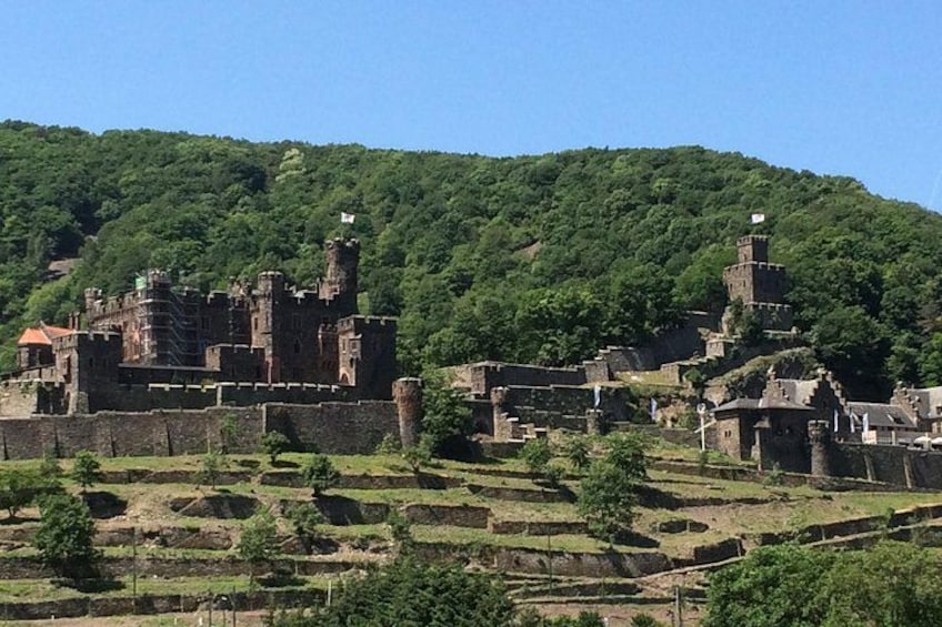 A medieval castle on a hill with terraced fields below. 5