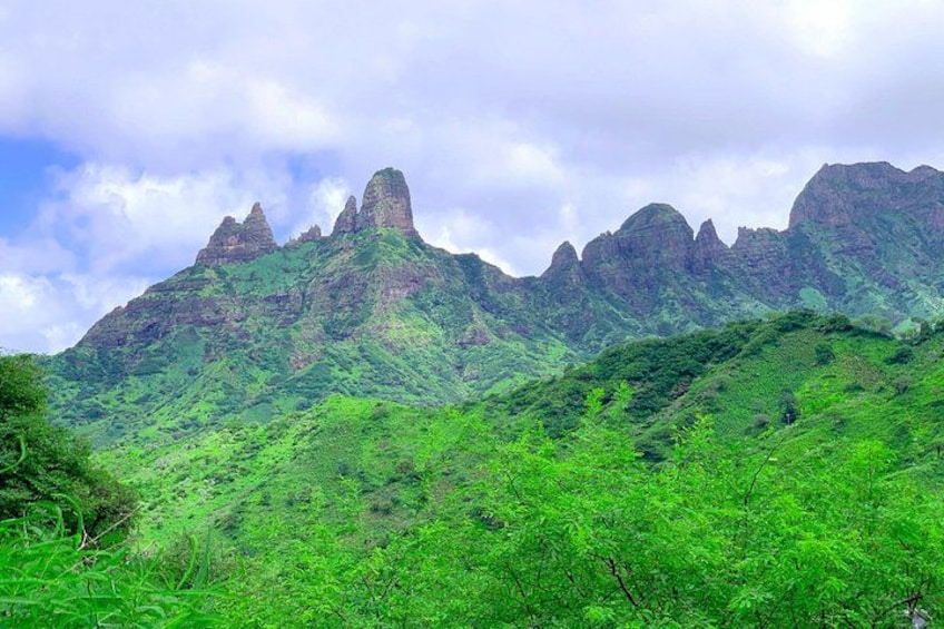 Un paisaje montañoso con vegetación exuberante y prominentes picos rocosos. 1