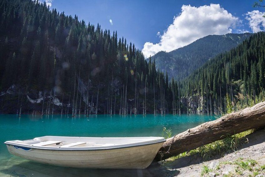 A boat on a turquoise lake surrounded by dense forest and mountains. 1
