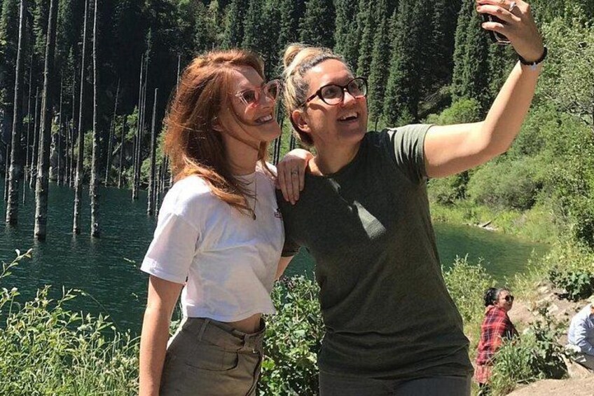 Two people taking a selfie with a lake and trees in the background. 5