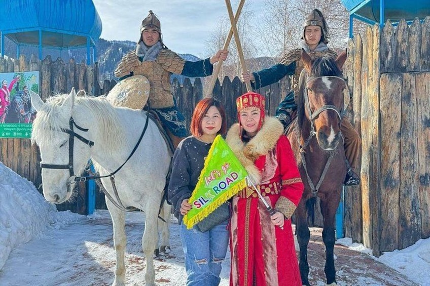 Paisaje nevado con cercas de madera, un caballo blanco y personas con vestimenta tradicional. 2