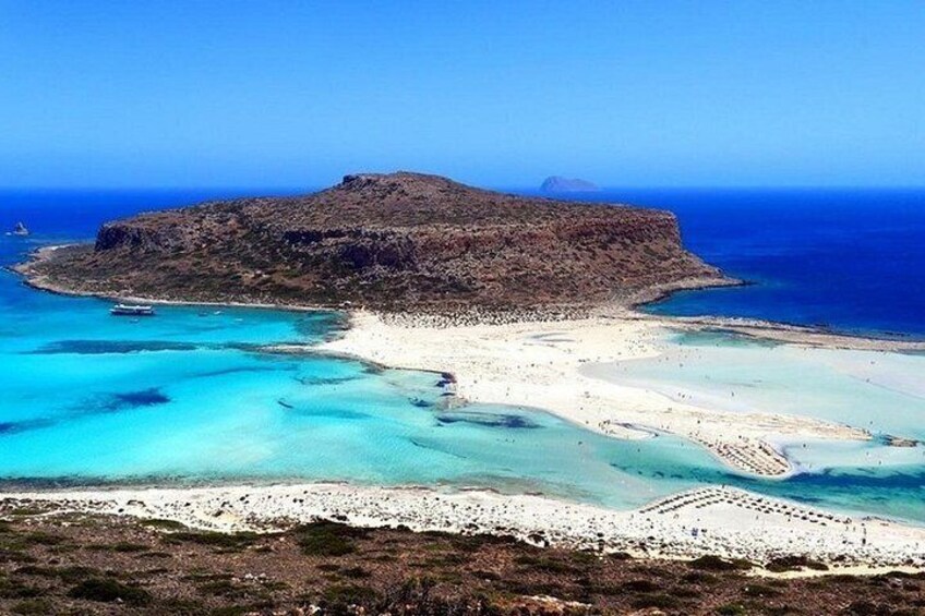 Un paisaje costero con una isla rocosa destacada, aguas turquesas cristalinas y una playa arenosa. 5