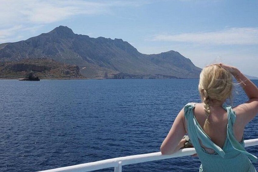 A person on a boat, water, and a mountain in the background. 2
