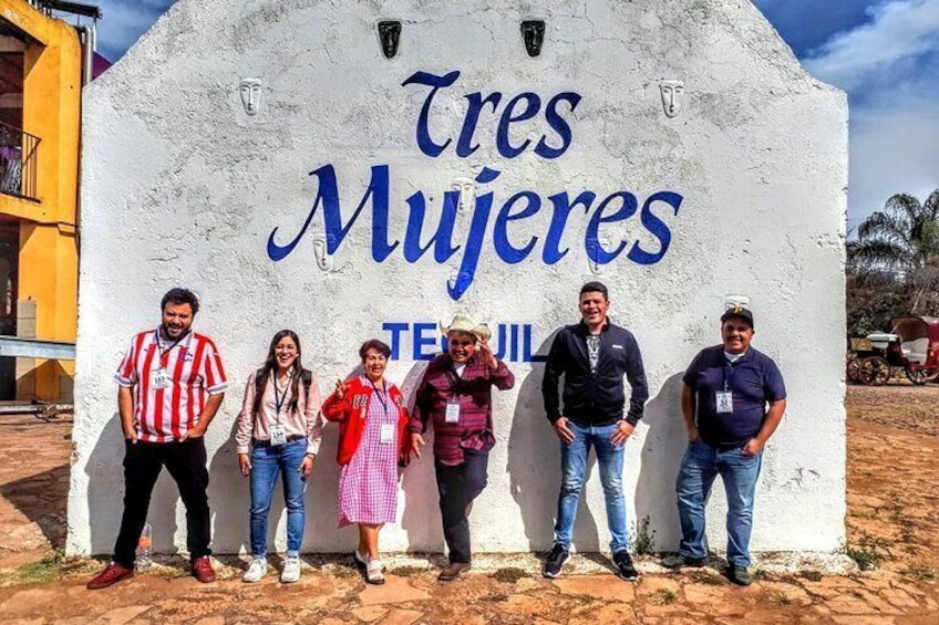 Un grupo de personas de pie frente a un cartel que dice 'Tres Mujeres'. 2