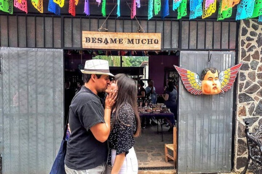 Una pareja besándose frente a una tienda llamada 'BESAME MUCHO'. 3