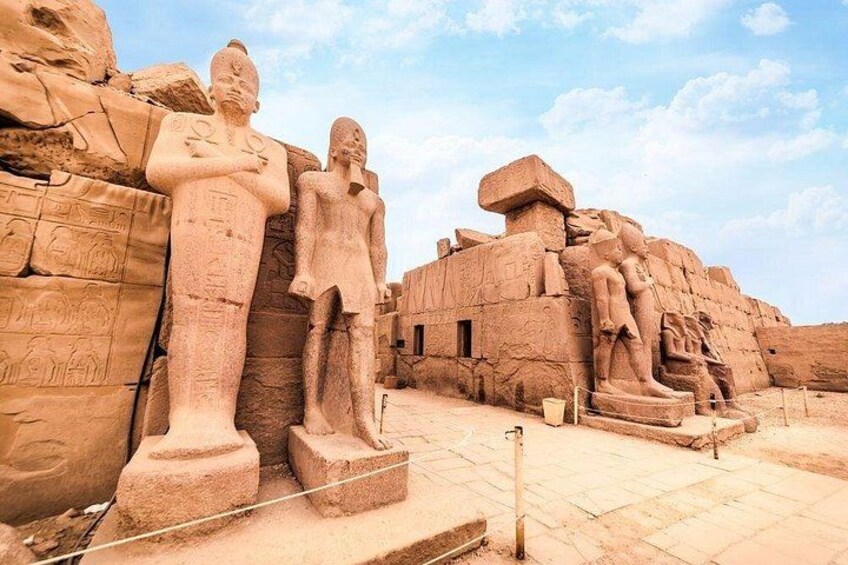 Ancient Egyptian statues and hieroglyphs on a rock face. 1