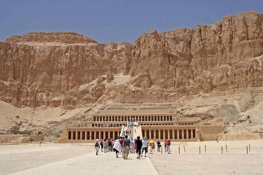 A large ancient Egyptian temple with a group of tourists in front. 3