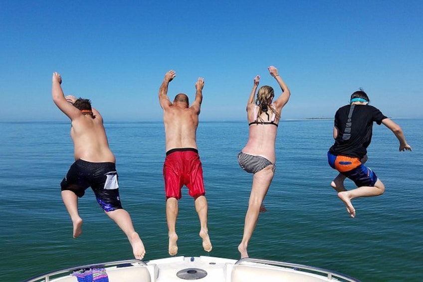Vier Personen springen von einem Boot ins Wasser. 3