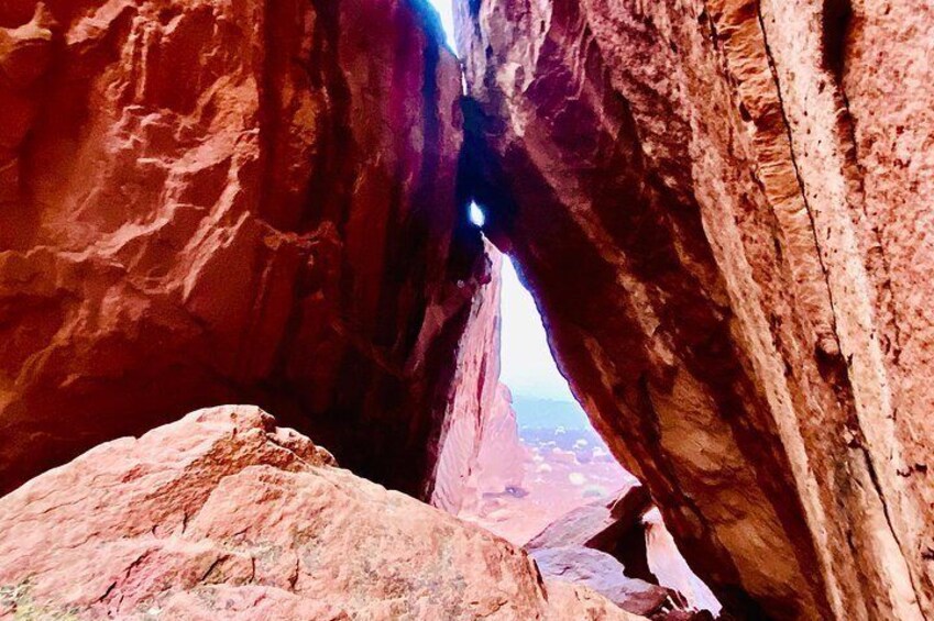 A canyon with a narrow passageway and a view of the landscape beyond. 5