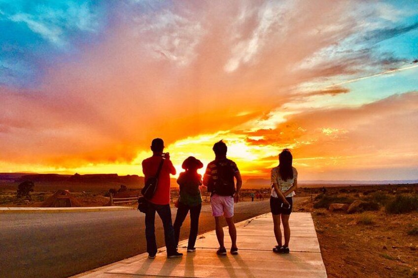 Un coucher de soleil sur lequel on voit quatre personnes debout sur un trottoir. 1