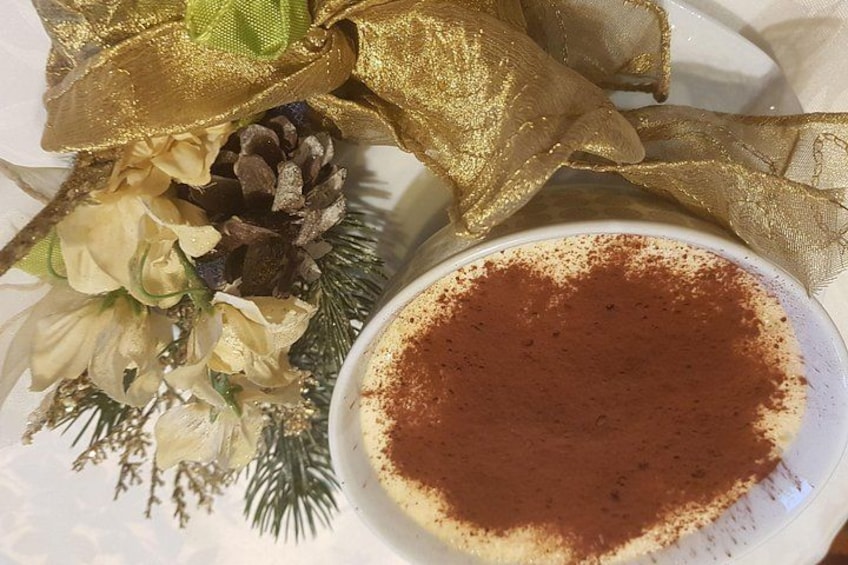 A plate with a dusting of cocoa powder, a pine cone, and decorative flowers. 2