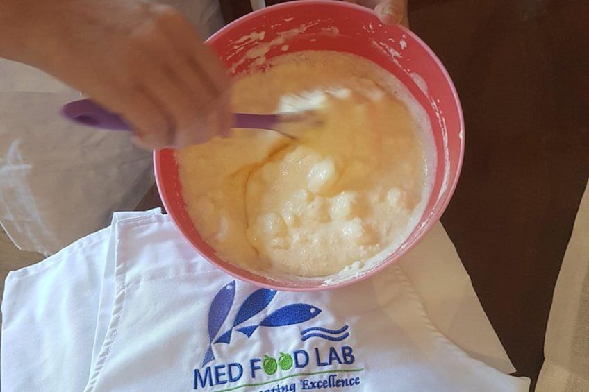 A person mixing a creamy substance in a red bowl. 5