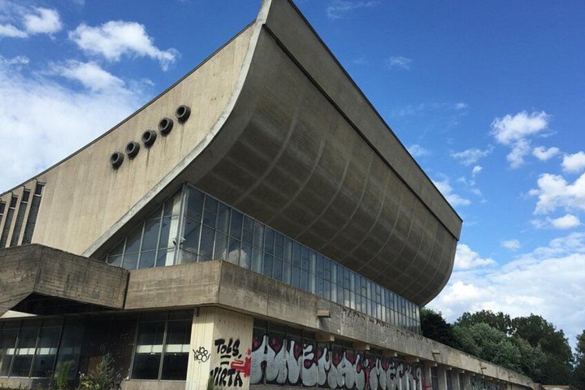 Un edificio moderno con fachada curva, ventanas amplias y grafitis en la parte inferior. 4