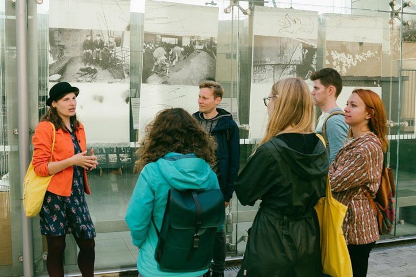 A group of people standing in front of a glass wall with historical photographs. 2