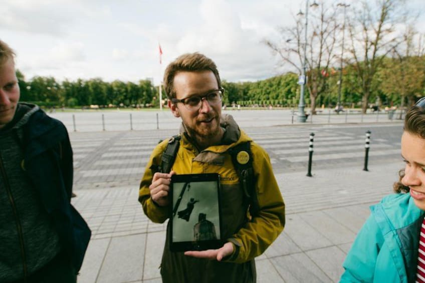 A person holding a map, standing on a paved area with trees and a flag in the background. 5