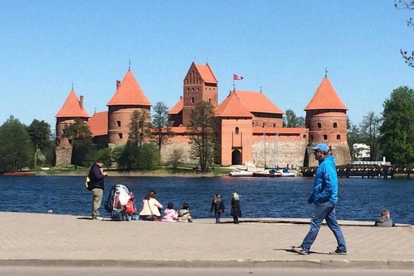 A castle with red roofs and towers by a body of water. 1