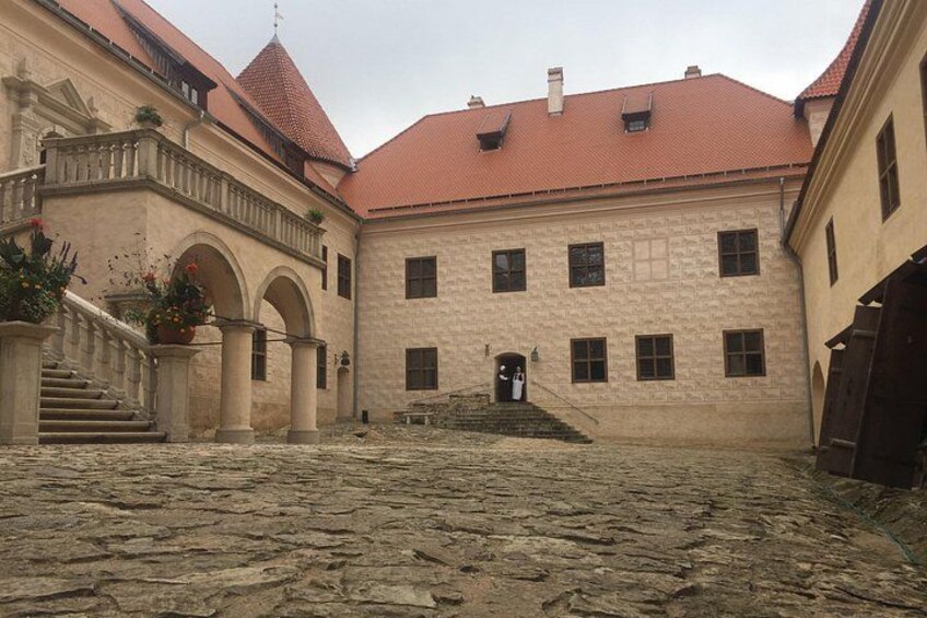 Un cortile con pavimento in pietra, un edificio con tetto rosso e una scala che conduce all'ingresso. 2