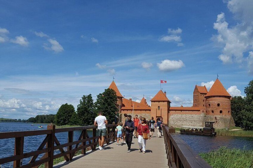Un puente de madera que conduce a un castillo histórico junto a un lago. 3