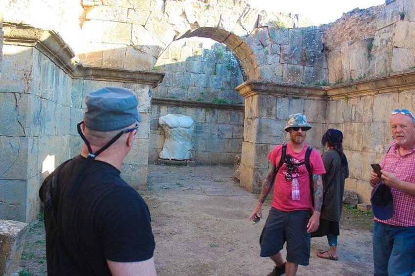 A group of people walking in an ancient stone structure with arches and columns. 3