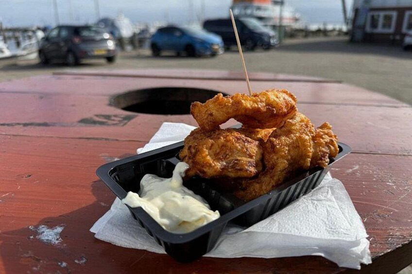 Un repas composé de poulet frit et d’un récipient de sauce, le tout posé sur une table rouge à l’extérieur. 4