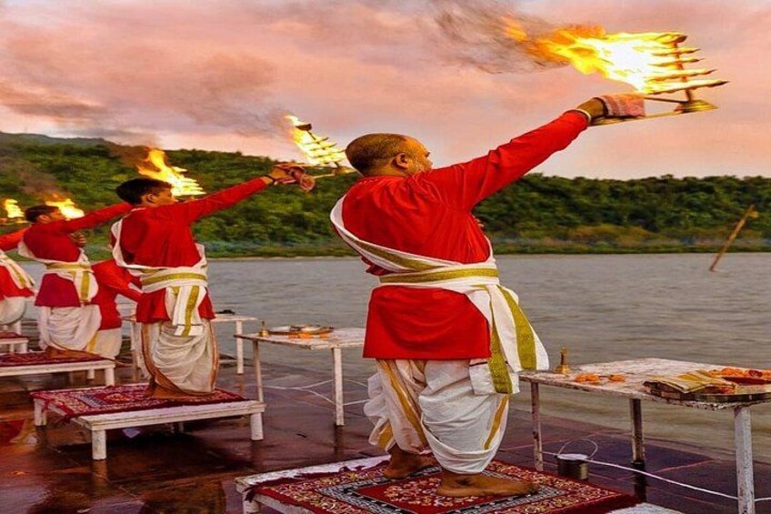 A group of people performing a ritual with fire on a lakeside platform. 1