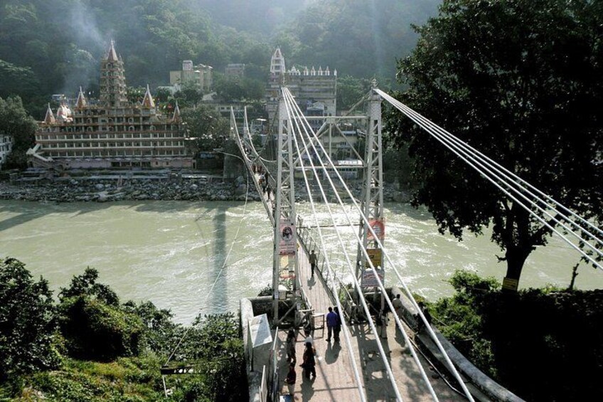 A suspension bridge over a river with a temple in the background. 3
