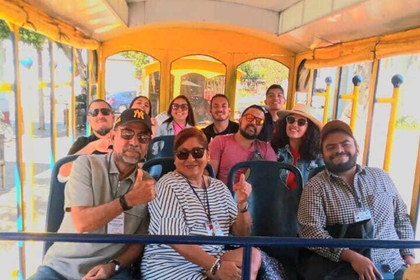 A group of people on a yellow bus with large windows, taking a photo. 1