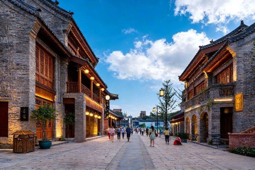 Eine historische Straße mit traditioneller Architektur, Kopfsteinpflaster und Passanten. 3