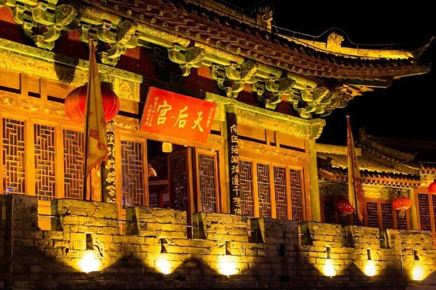 Ein traditionelles chinesisches Gebäude mit aufwendiger Architektur, beleuchtet durch warmes Licht. 5